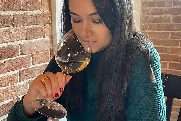 Donna degusta un vino bianco al calice durante una consulenza Wine Concierge in un ambiente elegante